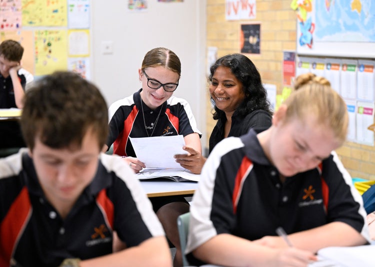 Staff member supporting a student in the background, two students in the foreground working