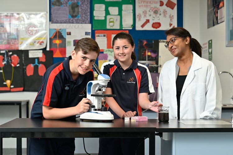 Student looking into a microscope and a student and staff member looking on