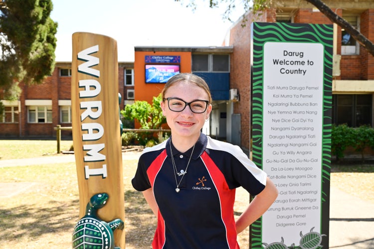 Student standing at the front of the school welcome signs Warami and Darug Welcome to Country
